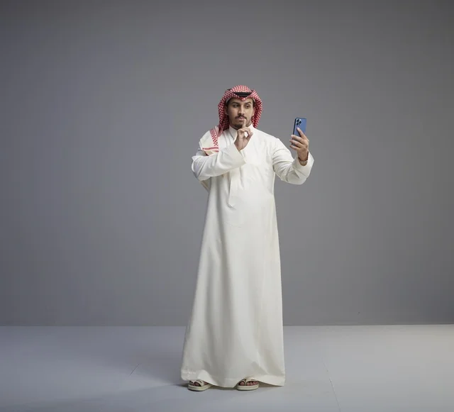 Saudi Man with Smartphone Making Silence Gesture