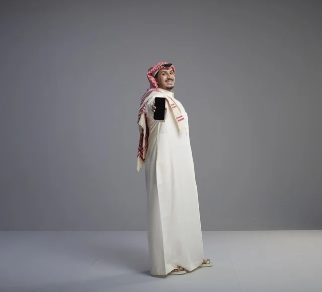 رجل سعودي يحمل نموذج هاتف ذكي في الاستوديو