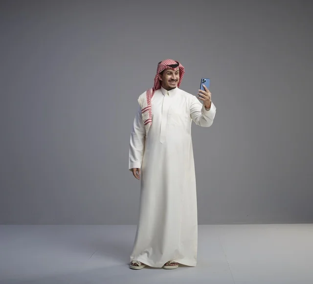 رجل سعودي يستخدم الهاتف الذكي بالزي التقليدي