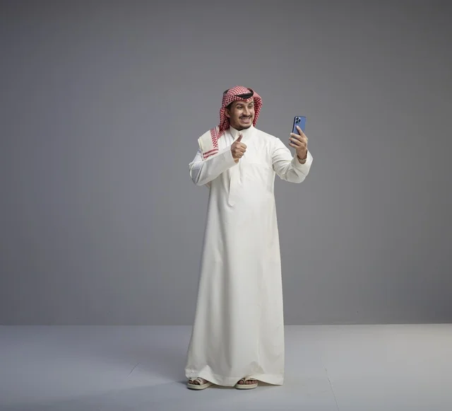 Saudi Man Using Smartphone with Thumbs Up Gesture