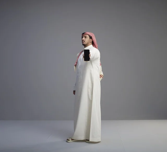 رجل سعودي يحمل نموذج هاتف ذكي في الاستوديو