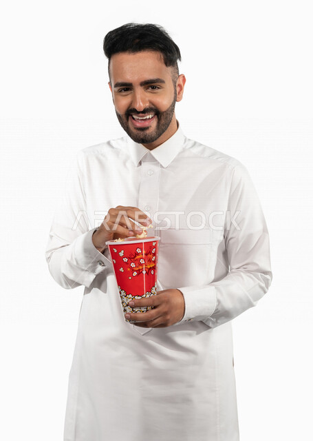 بورتريه لرجل عربي خليجي سعودي يحمل بيده علبة الفشار ، ايماءات الوجه واليدين تدل على المرح والاستمتاع ، مشاهدة الافلام داخل السينما ، متابعة افلام ومسلسلات كوميدية  ، أفلام وسينما 