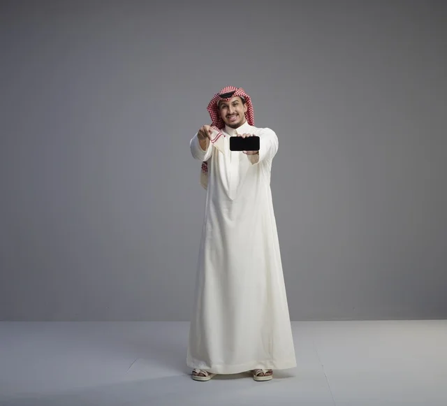 رجل سعودي يحمل هاتف ذكي بشاشة فارغة
