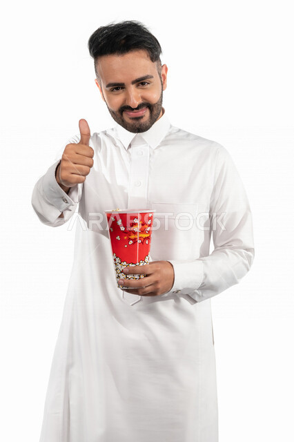 بورتريه لرجل عربي خليجي سعودي مبتسم يحمل بيده علبة الفشار ، ايماءات اليد تدل على الاعجاب  ، جودة افلام رائعة ، تقييم ايجابي ،الاعجاب بمشاهدة الافلام ، السينما السعودية الخليجية