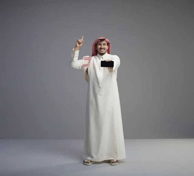 Saudi Man Holding Smartphone and Pointing Up