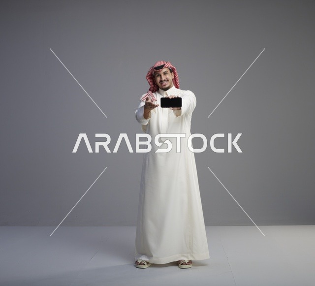 رجل سعودي يحمل هاتف ذكي في الاستوديو