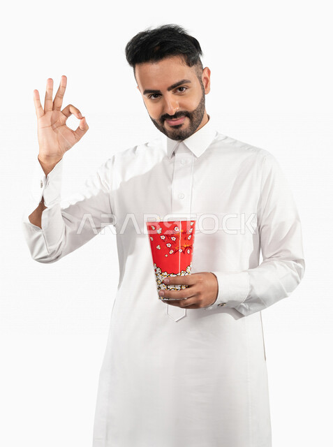 بورتريه لرجل عربي خليجي سعودي مبتسم يحمل بيده علبة الفشار ، ايماءات اليد تدل على الاعجاب  ، جودة افلام رائعة ، تقييم ايجابي ،الاعجاب بمشاهدة الافلام ، السينما السعودية الخليجية