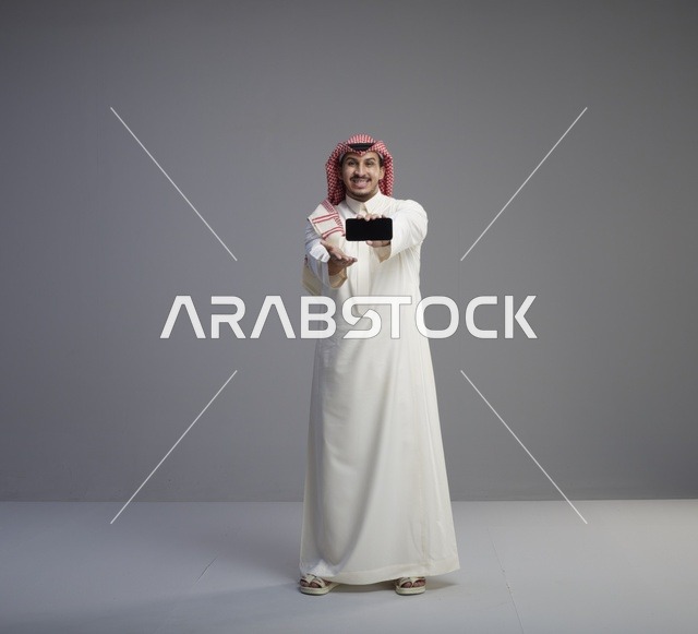 رجل سعودي يحمل نموذج هاتف ذكي في الاستوديو