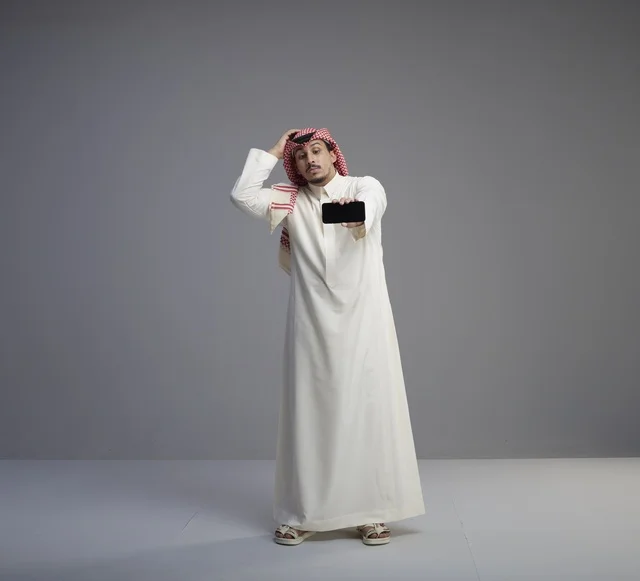 Saudi Man Holding Smartphone with Confused Expression