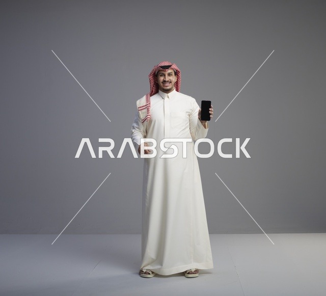 رجل سعودي يحمل هاتف ذكي بشاشة فارغة