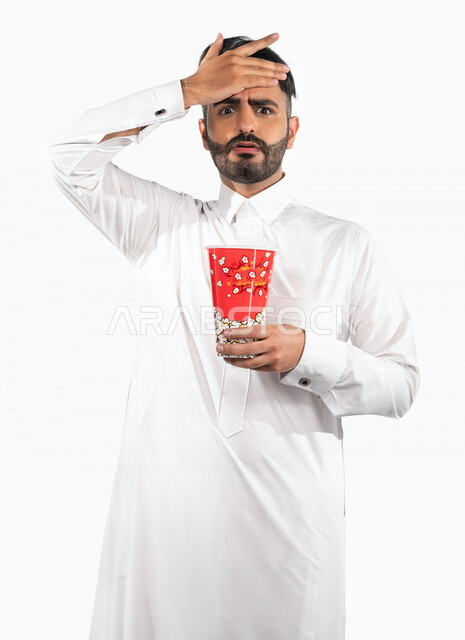 بورتريه لرجل عربي خليجي سعودي يحمل بيده علبة الفشار ، ايماءات الوجه واليدين تدل على الحماس والدهشة ، مشاهدة الافلام داخل السينما ، متابعة افلام الاثارة والاكشن ، أفلام وسينما
