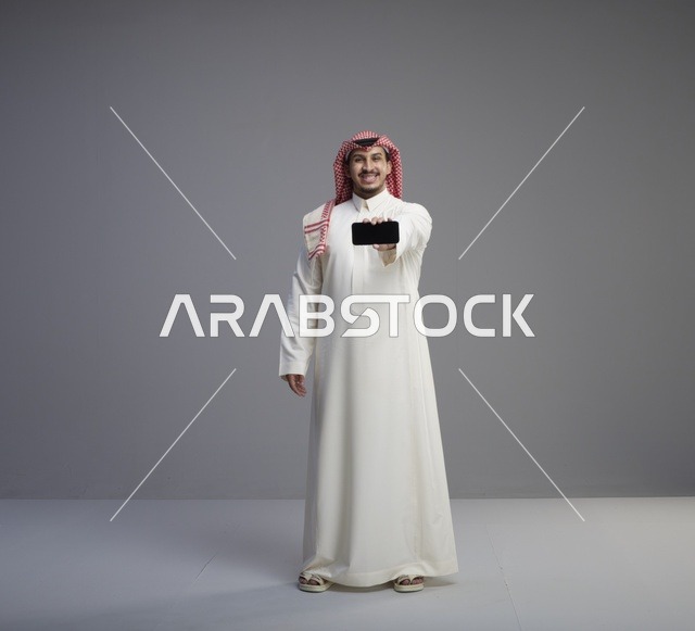 رجل سعودي يحمل هاتف ذكي في استوديو