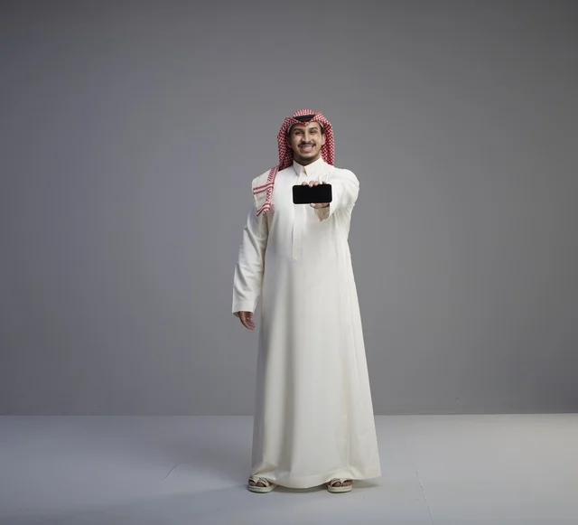 Saudi Man Holding Horizontal Smartphone Studio Portrait