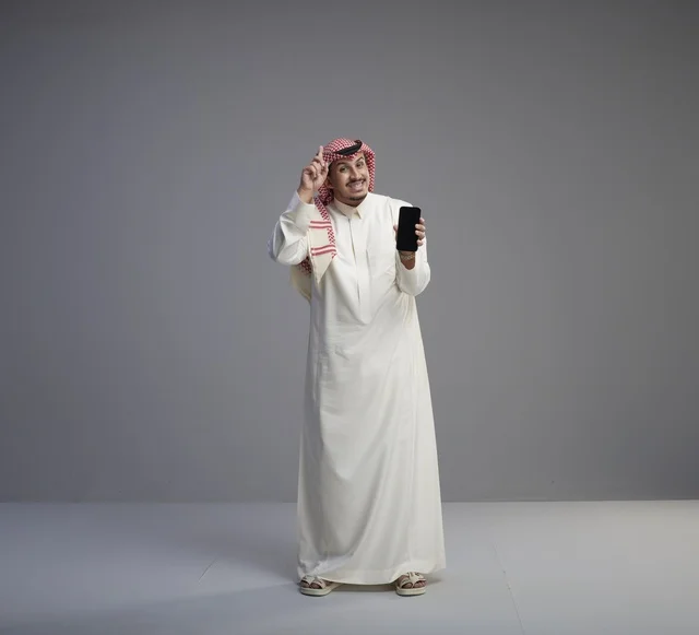 Saudi Man Holding Smartphone against Gray Background