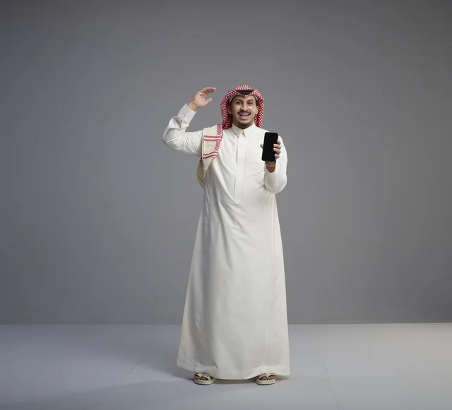 Saudi Man Holding Smartphone in Traditional Dress