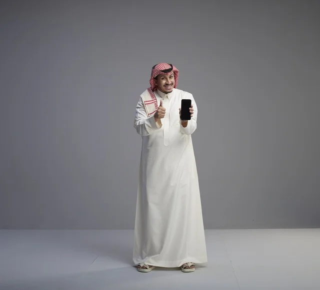 Saudi Man Holding Smartphone with Thumbs Up Gesture