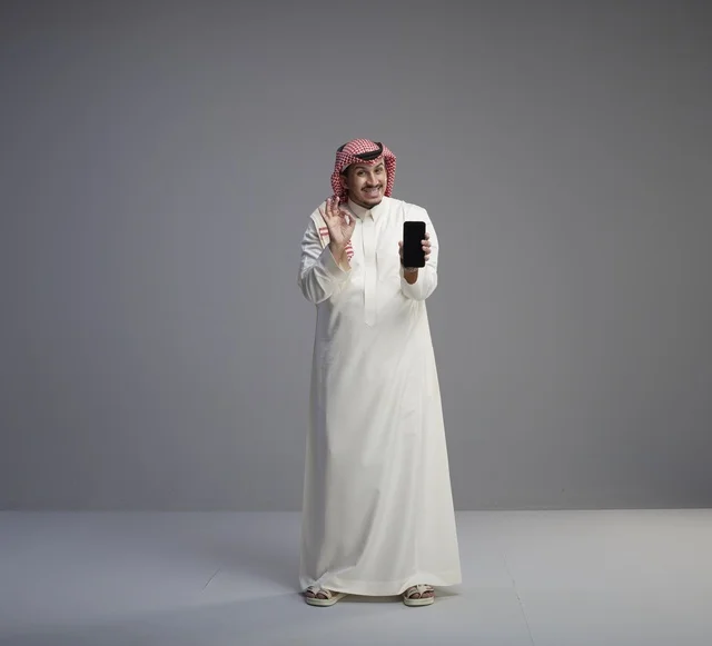 Saudi Man Holding Smartphone with OK Gesture Studio Shot