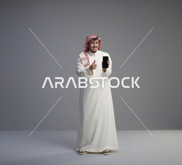 رجل سعودي يحمل هاتف ذكي مع علامة الإعجاب