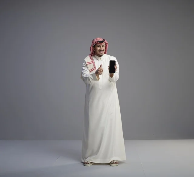 Saudi Man Holding Smartphone with Thumbs Up Gesture