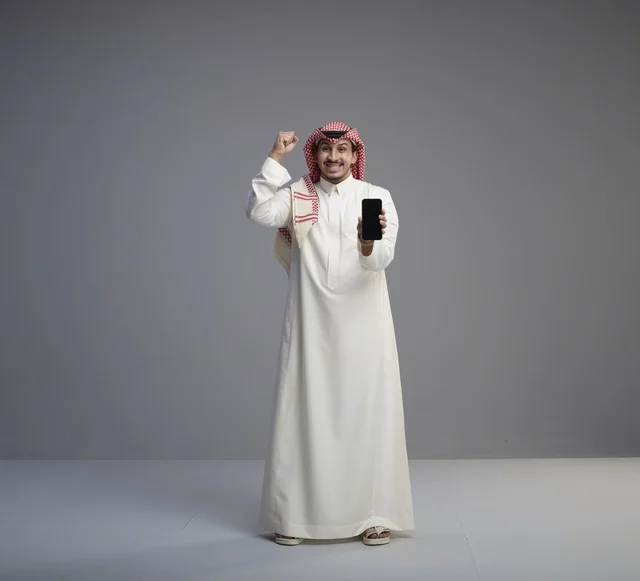 Saudi Man Holding Smartphone with Victory Gesture Studio