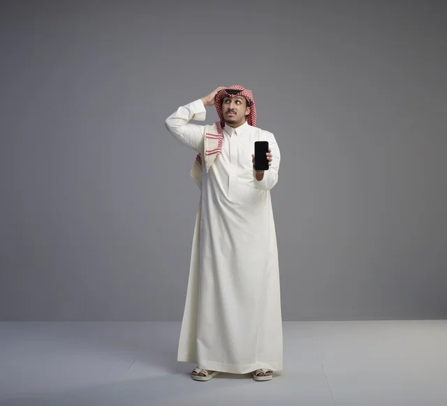 Saudi Man Holding Smartphone with Confused Expression