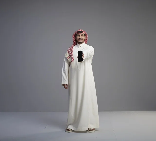 رجل سعودي يحمل هاتف ذكي بالزي التقليدي