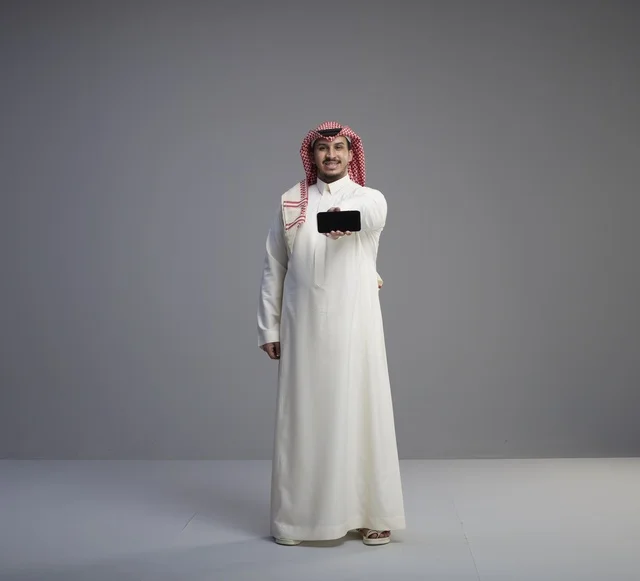 رجل سعودي يحمل نموذج هاتف ذكي في الاستوديو