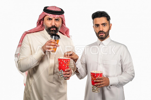 بورتريه لرجلان عربيان خليجيان سعوديان يحملان علبة الفشار ، ايماءات الوجه واليدين تدل على الحماس والدهشة ، مشاهدة الافلام داخل السينما ، متابعة افلام الرعب والاكشن ، أفلام وسينما