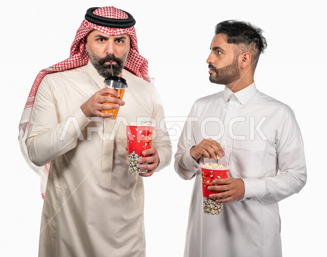 بورتريه لرجلان عربيان خليجيان سعوديان يحملان علبة الفشار ، ايماءات الوجه واليدين تدل على الحماس والدهشة ، مشاهدة الافلام داخل السينما ، متابعة افلام الرعب والاكشن ، أفلام وسينما