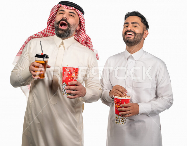 بورتريه لرجلان عربيان خليجيان سعوديان يحملان علبة الفشار ، ايماءات الوجه واليدين تدل على المرح والاستمتاع ، مشاهدة الافلام داخل السينما ، متابعة افلام ومسلسلات كوميدية  ، أفلام وسينما 