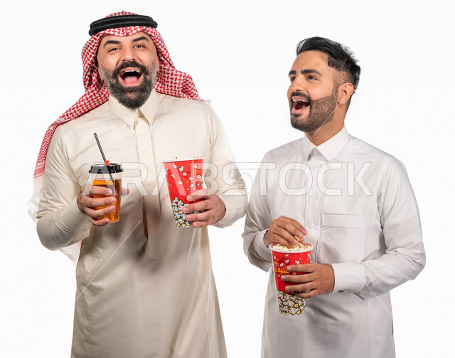 بورتريه لرجلان عربيان خليجيان سعوديان يحملان علبة الفشار ، ايماءات الوجه واليدين تدل على المرح والاستمتاع ، مشاهدة الافلام داخل السينما ، متابعة افلام ومسلسلات كوميدية  ، أفلام وسينما 