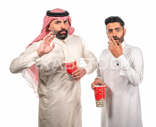 بورتريه لرجلان عربيان خليجيان سعوديان يحملان علبة الفشار ، ايماءات الوجه واليدين تدل على الحماس والدهشة ، مشاهدة الافلام داخل السينما ، متابعة افلام الرعب والاكشن ، أفلام وسينما 