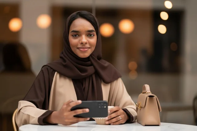 Saudi Woman Wearing Hijab Using Smartphone in Cafe