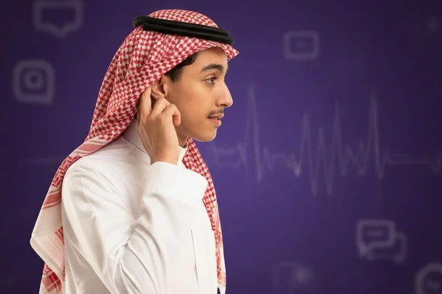 شاب سعودي بالزي التقليدي أمام خلفية رقمية بنفسجية