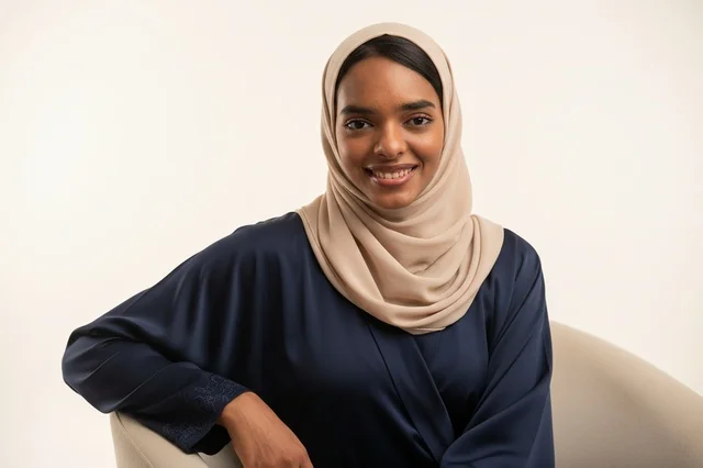 A Saudi woman in a navy abaya and a beige hijab.