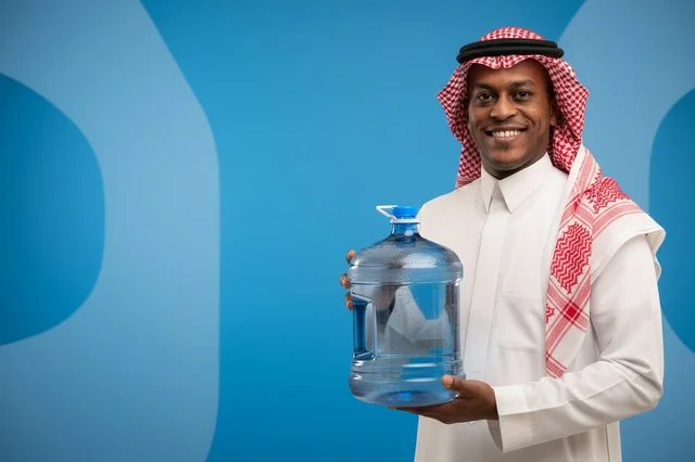 رجل سعودي بالزي التقليدي يحمل جالون مياه شرب كبير