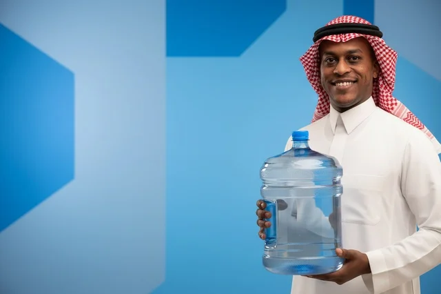 رجل سعودي بالزي التقليدي يحمل جالون مياه شرب كبير