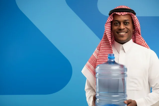 رجل سعودي بالزي التقليدي يحمل جالون مياه شرب كبير رجل سعودي بالزي التقليدي يحمل جالون مياه شرب كبير