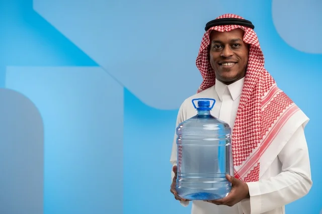 رجل سعودي بالزي التقليدي يحمل جالون مياه شرب كبير