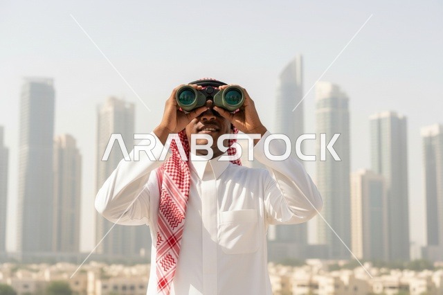 رجل سعودي مع منظار أمام أفق مدينة دبي