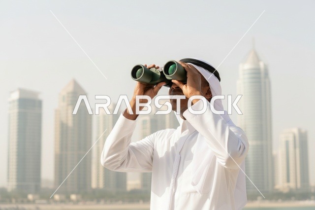 رجل إماراتي مع منظار ينظر إلى أفق المدينة