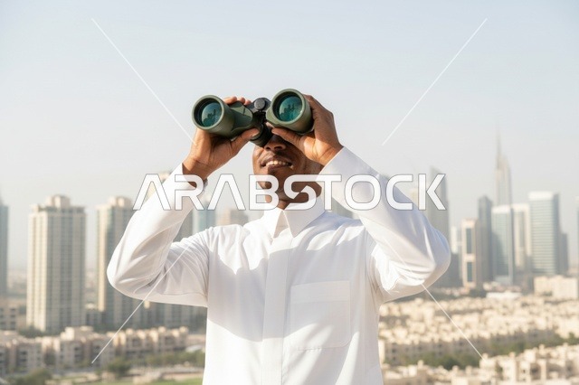رجل إماراتي يستخدم المنظار مع خلفية أفق المدينة