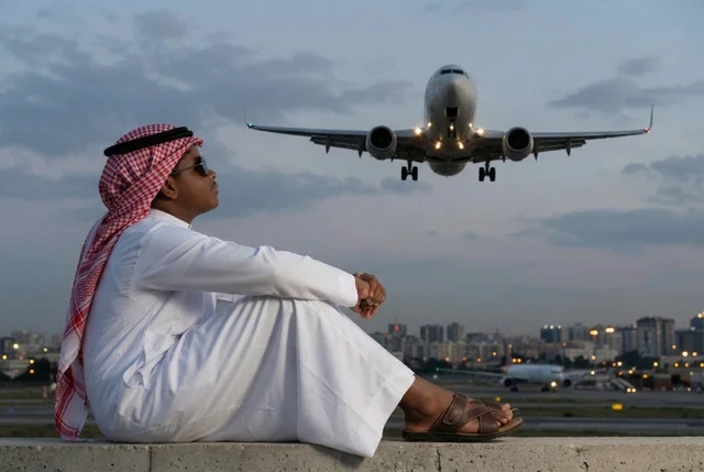 Saudi Man at Airport with Airplane Landing at Dusk