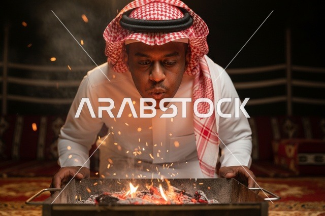 رجل سعودي ينفخ في الفحم داخل خيمة شتوية