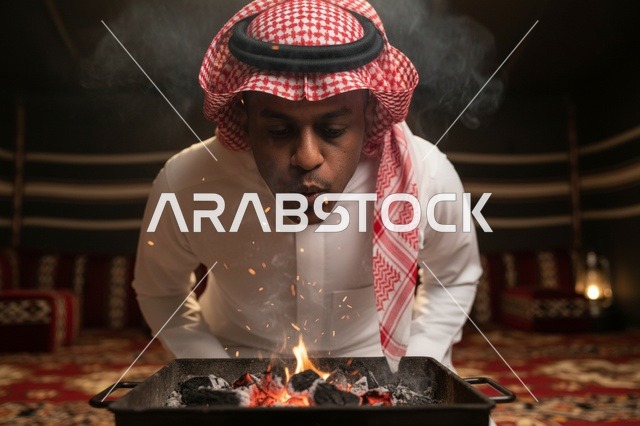 رجل سعودي ينفخ في الجمر المشتعل داخل خيمة