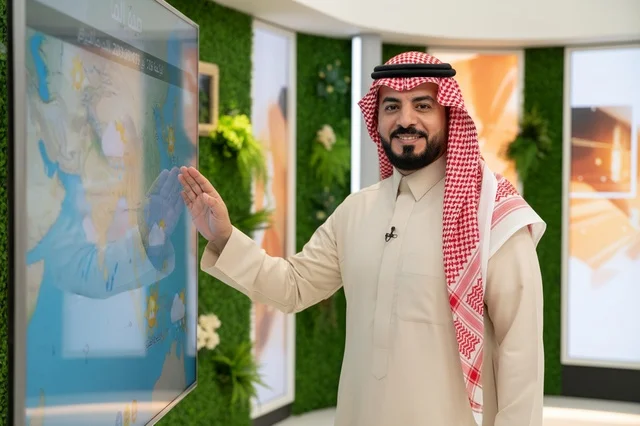 Saudi Weatherman in Traditional Thobe at Digital Screen