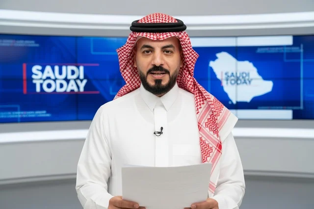 Saudi Male News Anchor in Television Studio Holding Papers