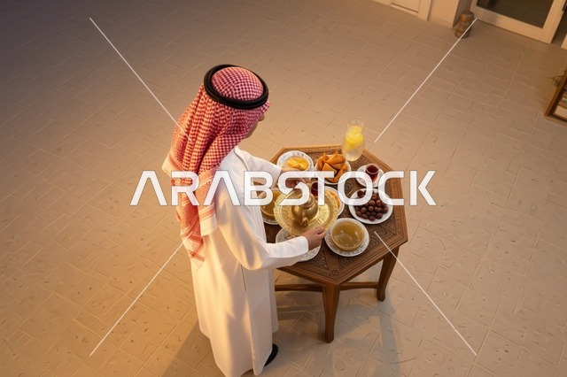 رجل سعودي يجهز طاولة القهوة العربية والضيافة التقليدية
