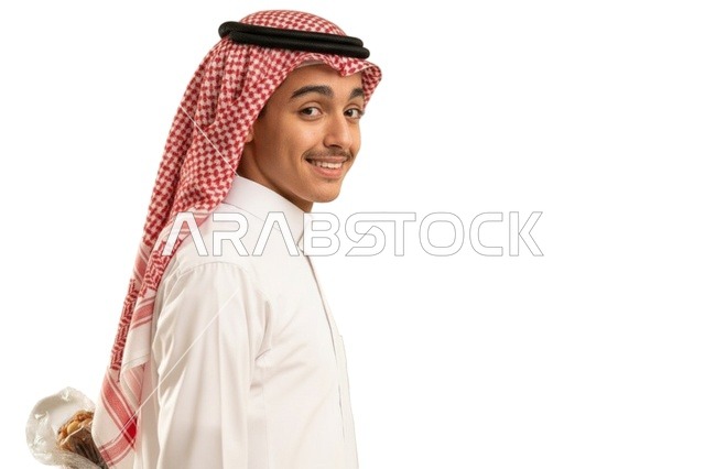 شاب سعودي بالثوب التقليدي يحمل باقة زهور خلف ظهره