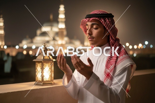 رجل سعودي يدعو بجانب المسجد مع فانوس في الليل